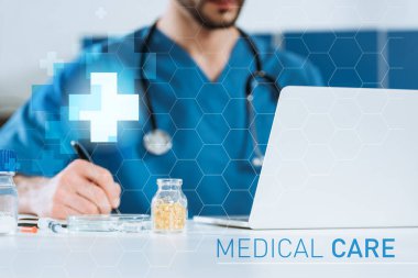 Genç doktorun laptopun yanına yazı yazarken seçici odak noktası ve ilaç içeren kap, tıbbi illüstrasyon