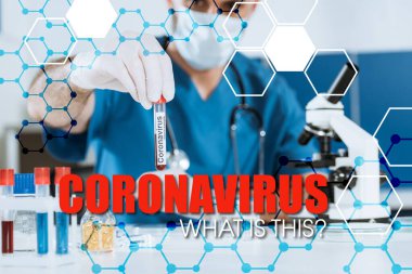 Tıbbi maskeli ve lateks eldivenli bilim adamlarının seçici odak noktası Coronavirus yazıtlı test tüpü tutuyor.