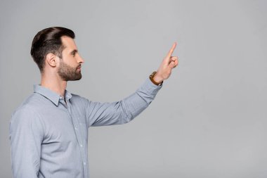 Yakışıklı iş adamının gri üzerine parmak gösteren yan görünüşü 