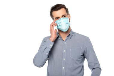 Medikal maskeli ve tişörtlü iş adamı beyaz telefondan izole edilmiş bir şekilde konuşuyor. 