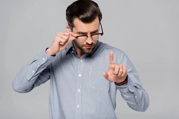 Homem Negócios Bonito Tocando Óculos Apontando Com Dedo Isolado Cinza — Fotografia de Stock