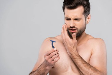 Gri üzerine izole edilmiş jilete bakan hoşnutsuz bir adam. 