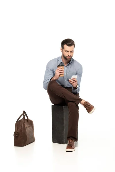Schöner Geschäftsmann Mit Smartphone Während Neben Tasche Auf Weiß Sitzt — Stockfoto
