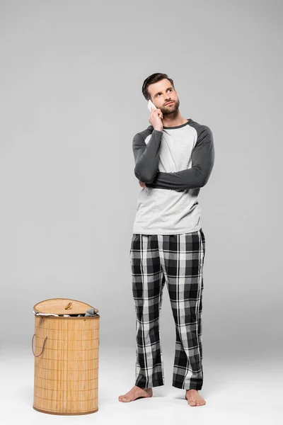 Hombre Guapo Hablando Teléfono Inteligente Cerca Cesta Ropa Aislado Gris — Foto de Stock