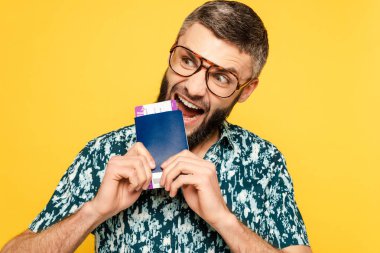 Gözlüklü çılgın sakallı adam sarı biletle pasaport yiyor.