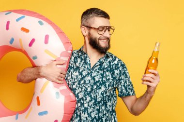 smiling bearded guy in glasses with donut swim ring and beer on yellow clipart