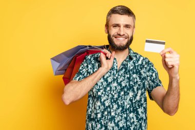 Alışveriş torbaları ve kredi kartıyla mutlu sakallı adam.