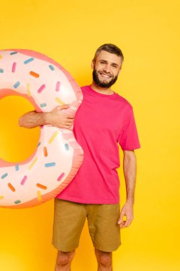 Sarı yüzüklü pembe tişörtlü mutlu sakallı adam.