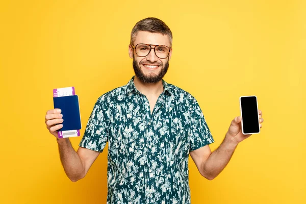 Uśmiechnięty Brodaty Facet Okularach Paszportem Biletem Pokazujący Smartfona Białym Ekranem — Zdjęcie stockowe