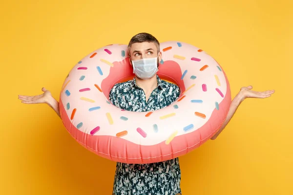 Cara Confuso Máscara Médica Com Donut Natação Mostrando Encolher Anel — Fotografia de Stock