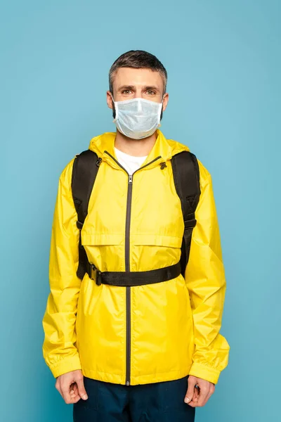 Entregador Máscara Médica Uniforme Amarelo Com Mochila Fundo Azul — Fotografia de Stock