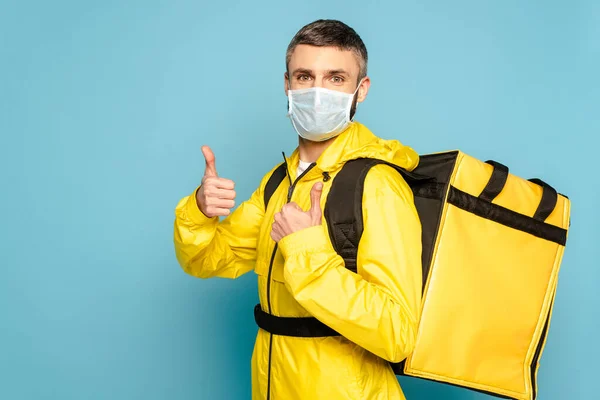 Deliveryman Medical Mask Yellow Uniform Backpack Showing Thumb Blue Background — Stock Photo, Image