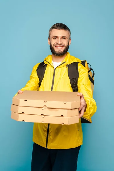 Usmívající Doručovatel Žluté Uniformě Batohem Drží Krabice Pizzy Modrém Pozadí — Stock fotografie