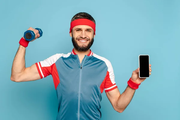 Sorrindo Desportista Elegante Exercitando Com Haltere Segurando Smartphone Fundo Azul — Fotografia de Stock