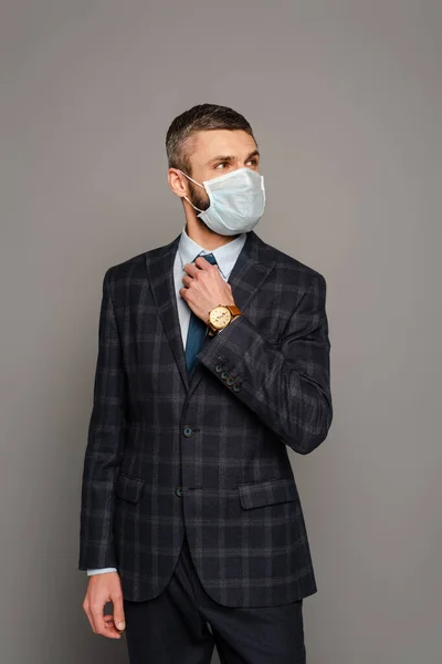Homem Negócios Bonito Máscara Médica Ajustando Gravata Fundo Cinza — Fotografia de Stock