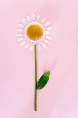 Beyaz çiçek yapraklarının yanındaki kahve fincanının üst görüntüsü pembe, anneler günü konsepti. 