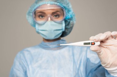 Koruyucu Google 'lardaki doktorların seçici odak noktası ve termometreyi gri renkte tutan tıbbi maske