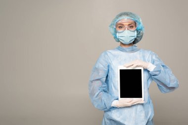 Google 'daki doktor ve tıbbi maske gri ekranda boş ekranlı dijital tablet tutuyor.