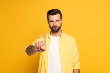 Sarı arka planda parmağı olan yakışıklı bir adam