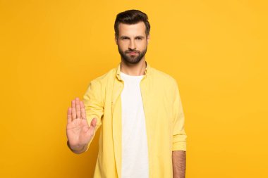 Handsome man showing stop sign on yellow background clipart