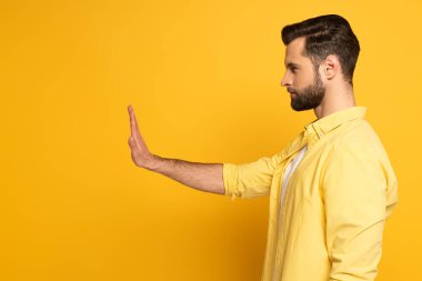 Side view of handsome man showing no sign on yellow background