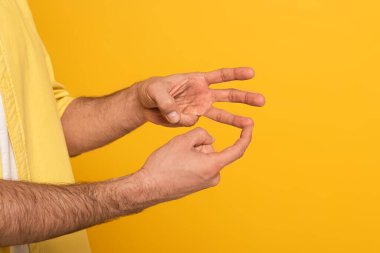 Cropped view of man showing gesture in deaf and dumb language isolated on yellow 