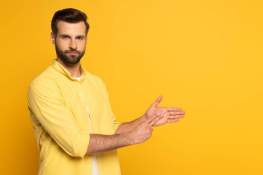 Sarı arkaplanda işaret dili kullanırken el kol hareketi yapan yakışıklı adam