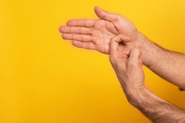 Cropped view of man showing gesture in deaf and dumb language isolated on yellow 