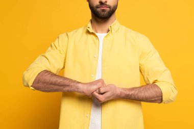 Cropped view of man showing cohesion sign in deaf and dumb language on yellow background clipart