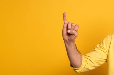 Cropped view of man showing letter in deaf and dumb language on yellow background