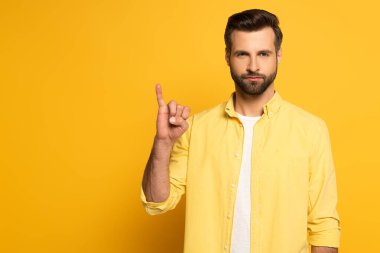 Handsome man showing letter in deaf and dumb language on yellow background