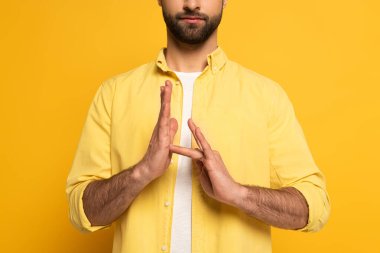 Cropped view of man showing sign in deaf and dumb language on yellow background
