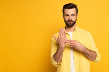 Sarı arkaplanda işaret diliyle hareket eden bir adam