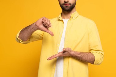 Cropped view of man showing sign in deaf and dumb language on yellow background