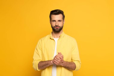 Handsome man showing marriage sign in deaf and dumb language on yellow background