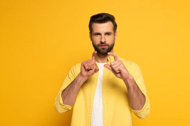 Bearded man showing gesture in deaf and dumb language on yellow background