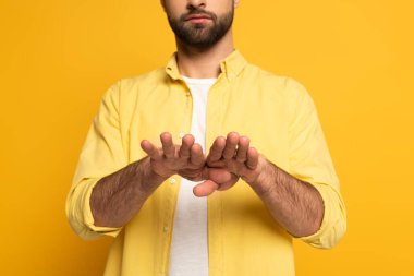 Cropped view of man showing gesture in deaf and dumb language on yellow background 