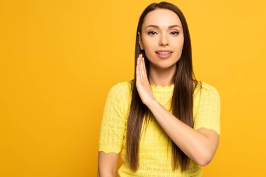 Attractive woman smiling and using deaf and dumb language isolated on yellow 