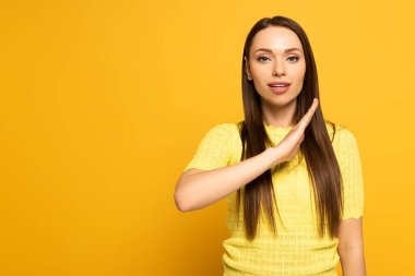Beautiful girl using deaf and dumb language on yellow background