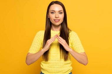 Smiling girl showing home gesture in deaf and dumb language on yellow background