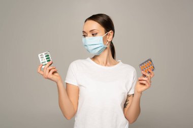 Young woman holding blisters with pills isolated on grey  clipart