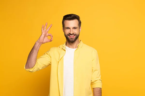 Bonito Homem Sorrindo Para Câmera Enquanto Mostra Sinal Fundo Amarelo — Fotografia de Stock