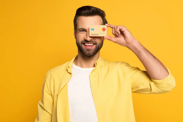 Homem Sorridente Cobrindo Olho Com Modelo Cartão Crédito Olhando Para — Fotografia de Stock