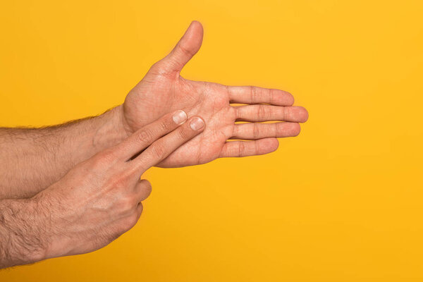 Cropped view of man showing gesture in deaf and dumb language with hands isolated on yellow 