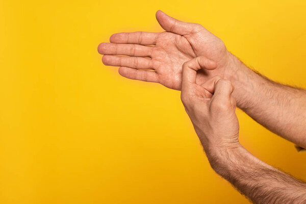 Cropped view of man showing gesture in deaf and dumb language isolated on yellow 