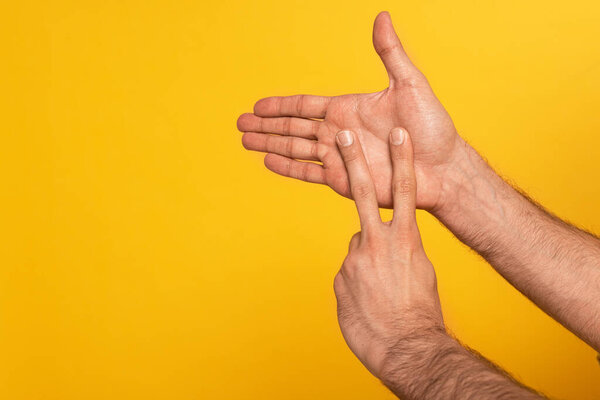Cropped view of man showing gesture in deaf and dumb language isolated on yellow 