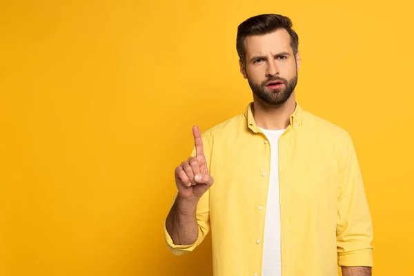 Nachdenklicher Mann Zeigt Mit Dem Finger Auf Gelben Hintergrund — Stockfoto