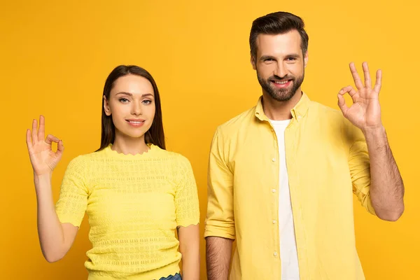 Sorrindo Casal Mostrando Gesto Olhando Para Câmera Fundo Amarelo — Fotografia de Stock