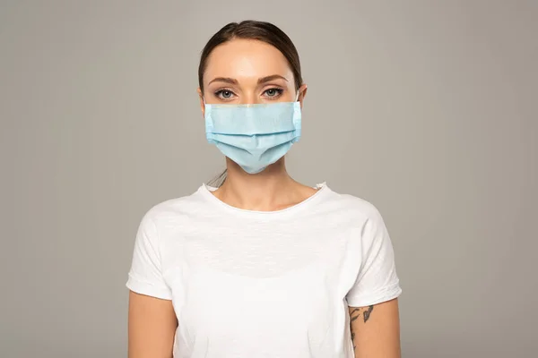 Tıbbi Maskeli Genç Bir Kadın Gri Kameraya Bakıyor — Stok fotoğraf