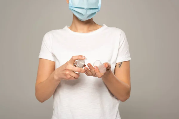 用灰色隔离的手部清洁剂拍摄戴口罩妇女的剪影 — 图库照片